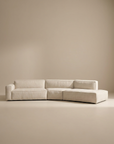 The Wooden Stories Baker Modular Sofa | Fabric • M9 is a modern, light beige sectional with clean lines and a right-side chaise, showcased against a plain, neutral background.
