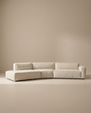The Baker Modular Sofa | Fabric • M9 by Wooden Stories is a modern beige sectional with clean lines and plush cushions. Featuring a customizable design and left chaise lounge, it creates an inviting L-shaped seating arrangement.
