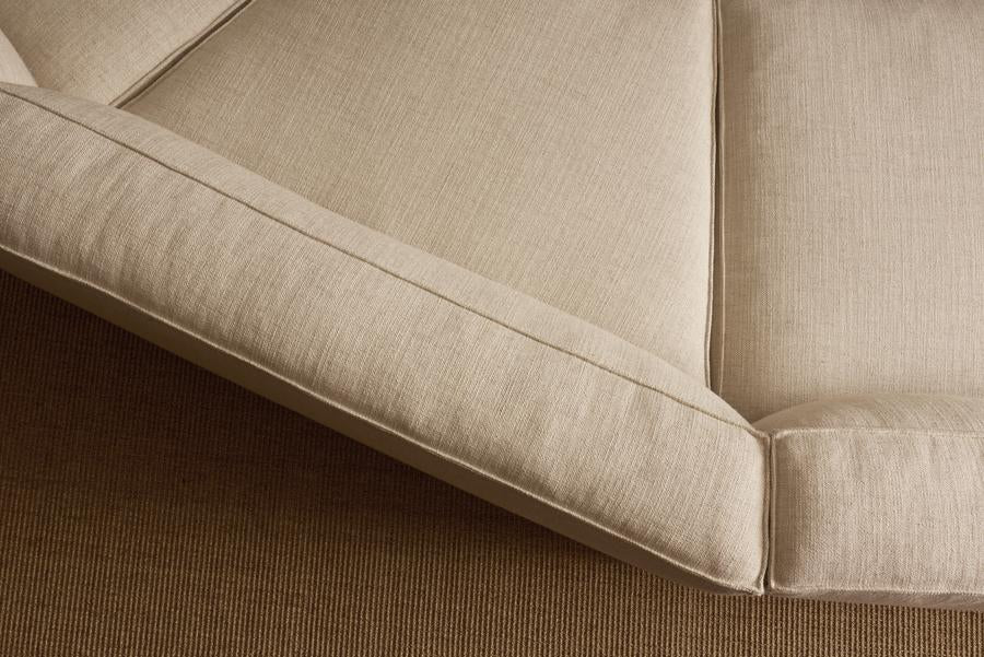Close-up of the corner of the Baker Modular Sofa | Fabric • M9 by Wooden Stories, featuring visible seams, shown on a brown textured carpet.