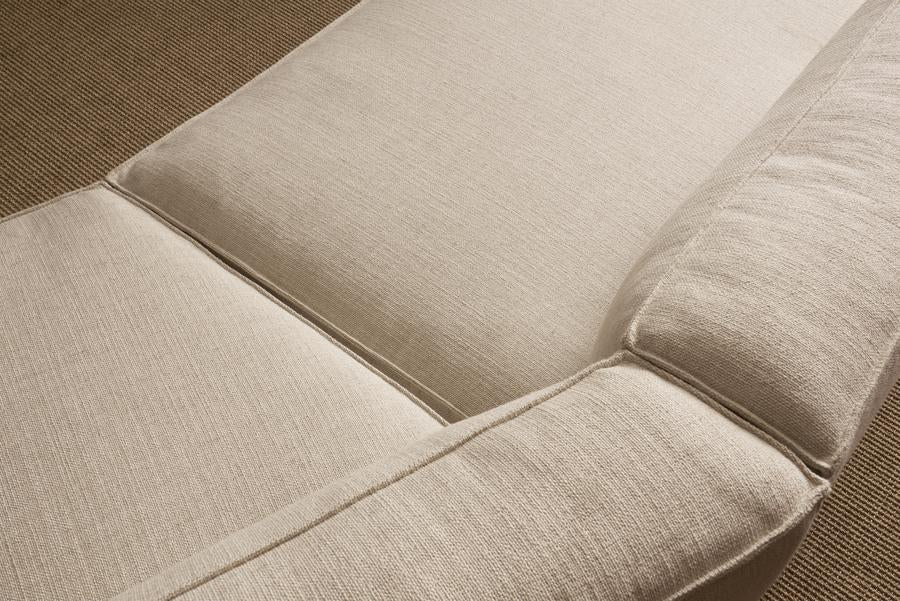 Close-up of the Baker Modular Sofa | Fabric • M9 by Wooden Stories, featuring beige textured upholstery and visible seams on a brown carpet—part of our customizable sectional Danish collection.