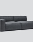 The Baker Modular Sofa | Fabric • M1 by Wooden Stories features a modern dark gray design with a low backrest and wide seat cushions, showcased against a plain light gray background.