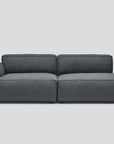 The Baker Modular Sofa | Fabric • M1 by Wooden Stories is a modern, dark gray sectional with a left armrest and spacious seating, shown against a plain light gray background.