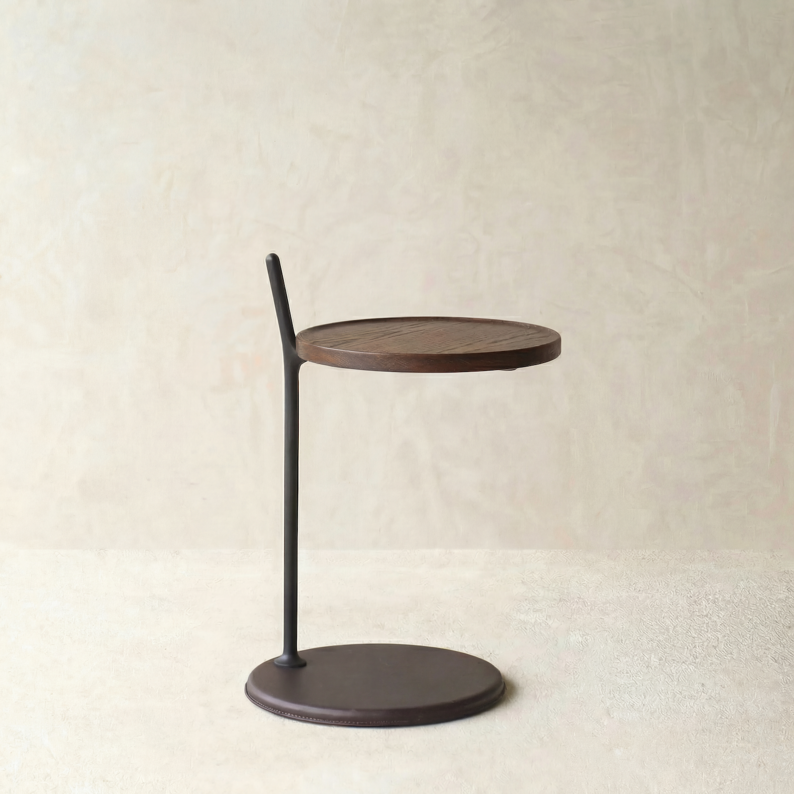 The Bystander Side Table by Wooden Stories features a compact, round solid wood top paired with a slender black metal rod and matching base, creating a modern accent piece for any space.