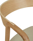 Close-up of the Wooden Stories Inlay Dining Chair in light oak and leather, featuring a smooth, curved plywood backrest, armrests with natural wood grain, and a light beige leather seat against a white background.