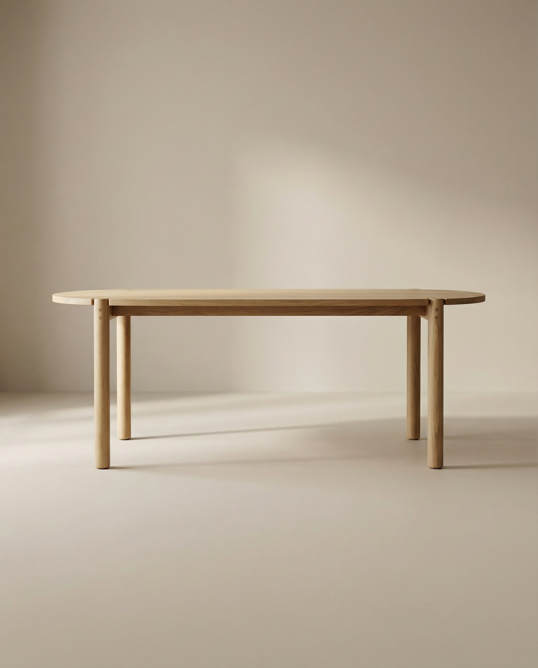 The Wooden Stories Cove Dining Table | Light Oak features solid American oak with rounded edges and four cylindrical legs, shown against a neutral beige background in a softly lit room.