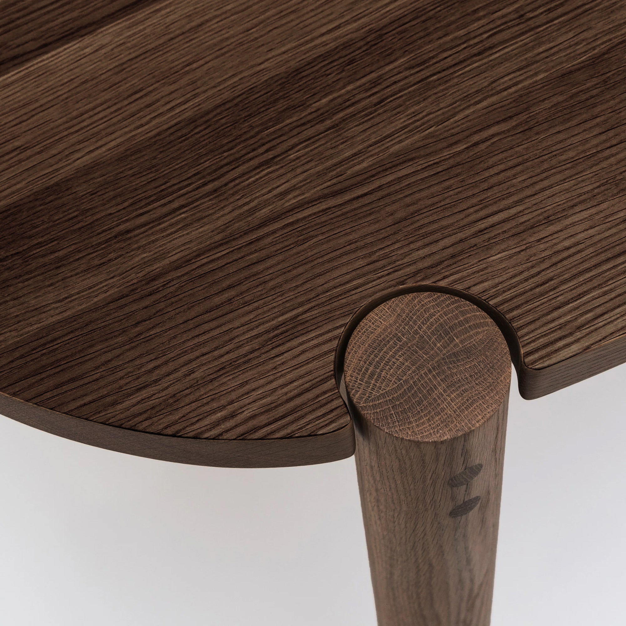 Close-up of the Cove Dining Table | Espresso Oak by Wooden Stories, featuring solid American oak in a dark finish and Danish-inspired design with a table leg fitting seamlessly into a carved notch.
