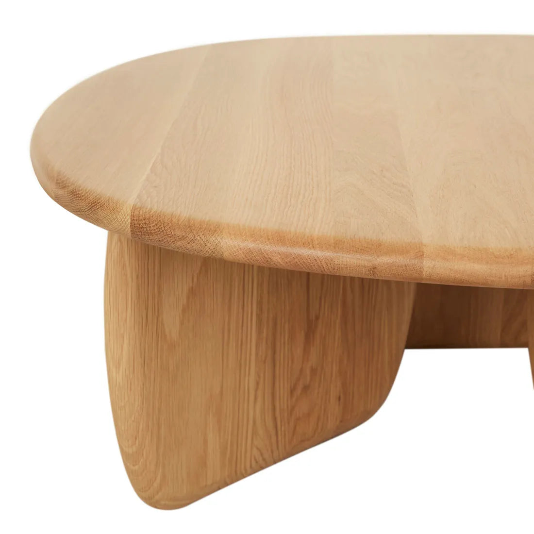 A close-up of the Eden Coffee Table by Wooden Stories in Light Oak, featuring a smooth, rounded top, thick curved legs, and a minimalist design that highlights its natural wood grain.