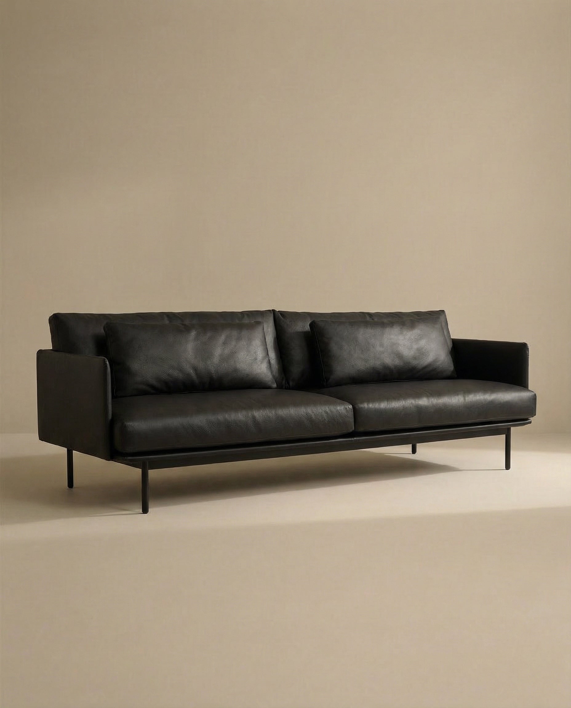 The SOBU Cherry Sofa | Leather is a modern black leather 3-seater with slim metal legs and Danish-inspired lines, shown against a beige backdrop—an ideal fit for contemporary living spaces.
