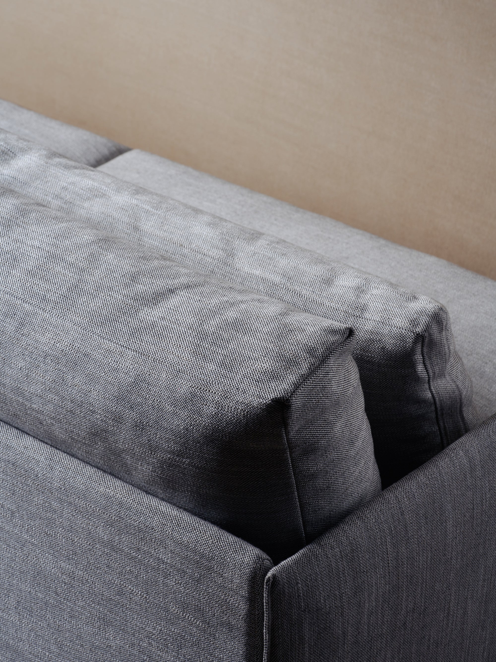 A close-up of the backrest and cushions of the Cherry Sofa 79" | Fabric by Wooden Stories in gray fabric, shown against a light beige wall—ideal for modern interiors.