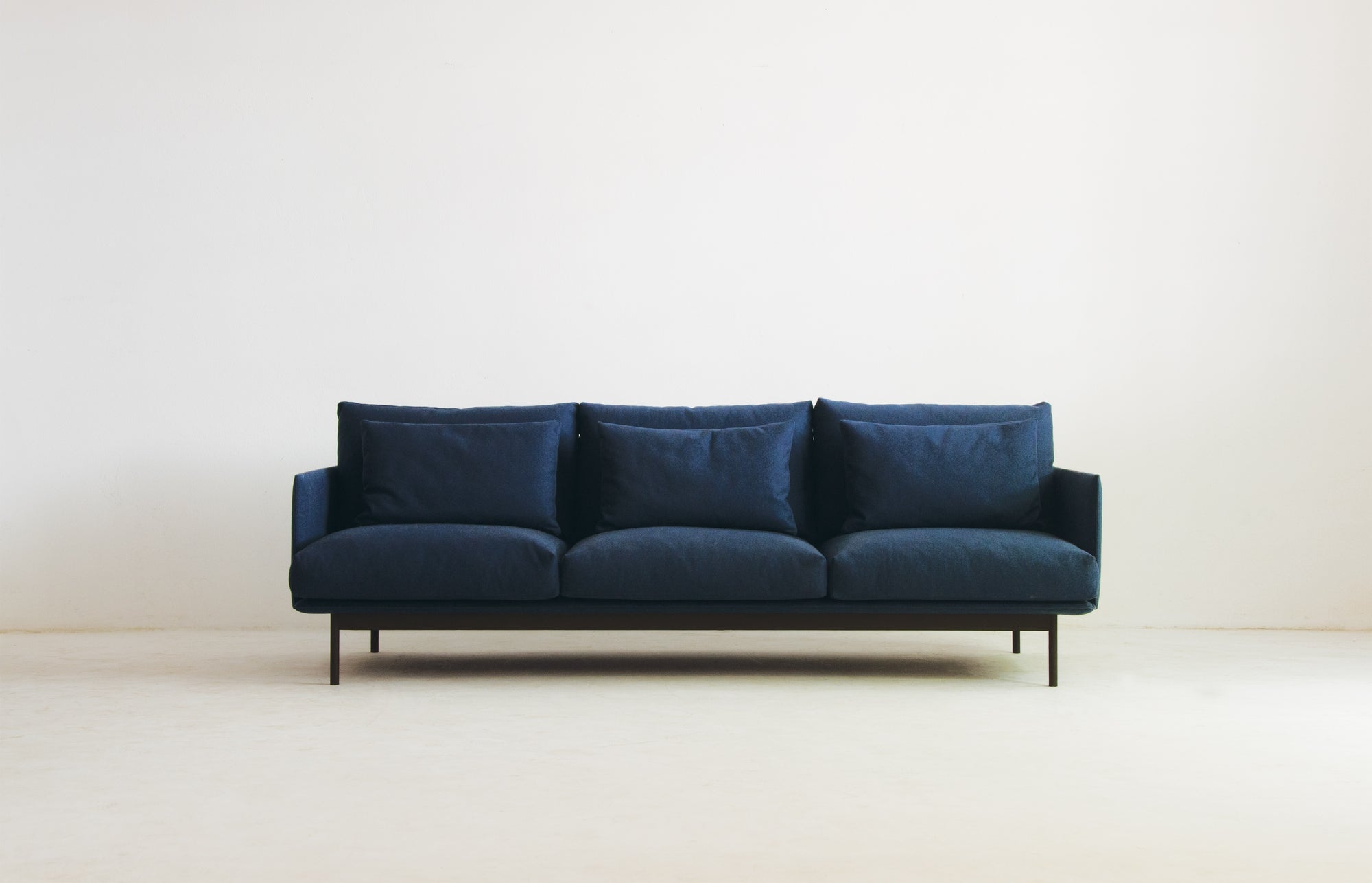 The Cherry Sofa 95" | Fabric by Wooden Stories features Danish-inspired minimalist design, three large cushions, slim black legs, and a clean look—an ideal centerpiece for modern living spaces.