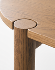 Close-up of the Cove Dining Table | Latte Oak by Wooden Stories, highlighting a round leg seamlessly integrated into the edge of the tabletop, with visible wood grain and joinery details crafted from solid American oak.