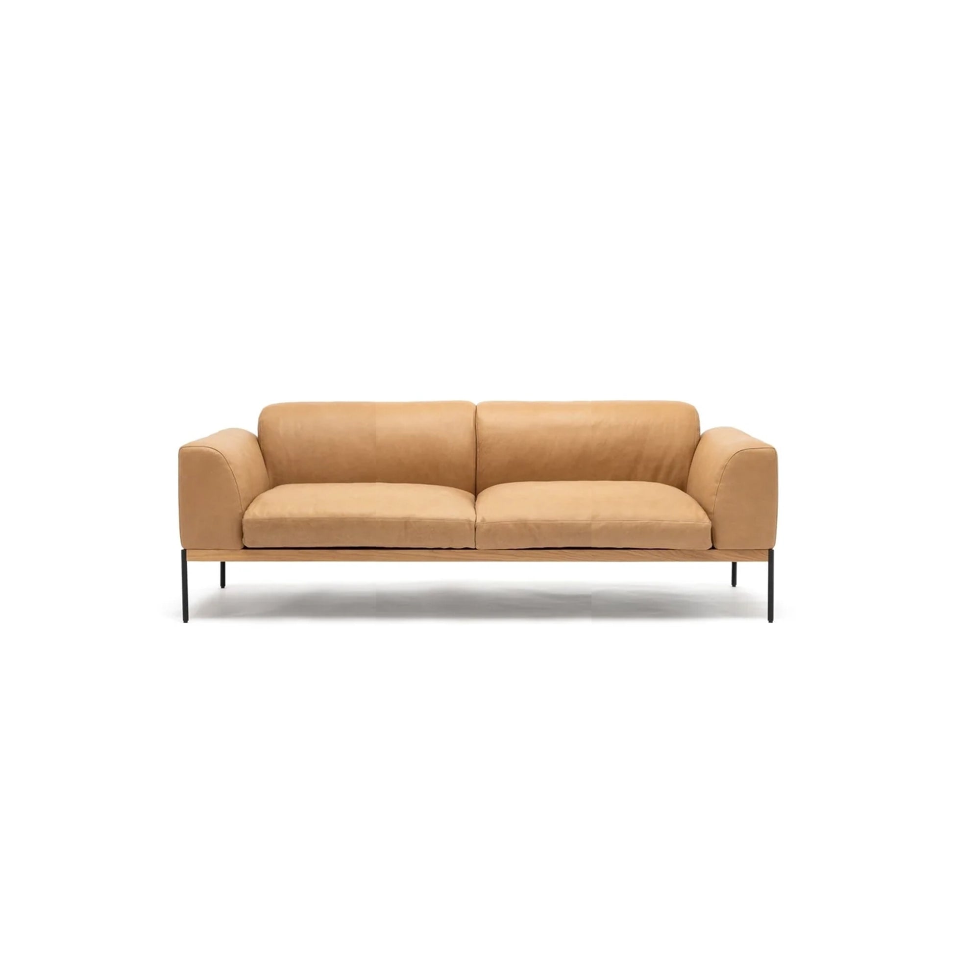 The Department Sofa 81" | Leather by Wooden Stories features modern tan leather, wide armrests, a solid wood base, and black metal legs, inspired by Danish collections and displayed on a plain white background.