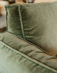 Close-up of Wooden Stories’ Attendant Lounge Chair | Fabric in green velvet, showcasing the plush upholstery and detailed seams on the backrest and armrest, set against a softly blurred background.