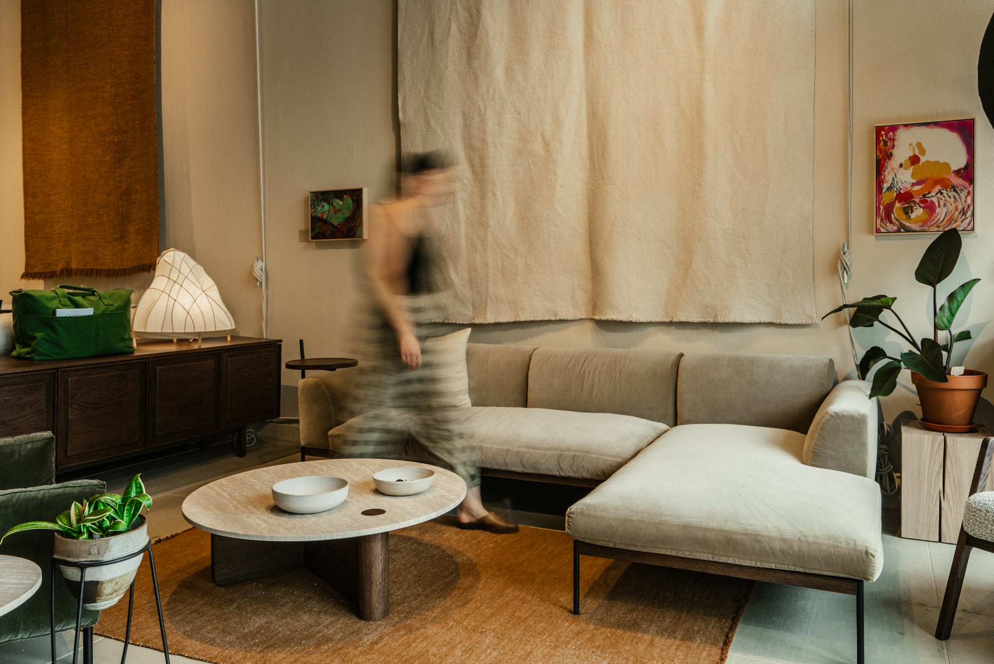 Modern living room with a beige sectional Department sofa, Pivot Round coffee table, and decorative elements.