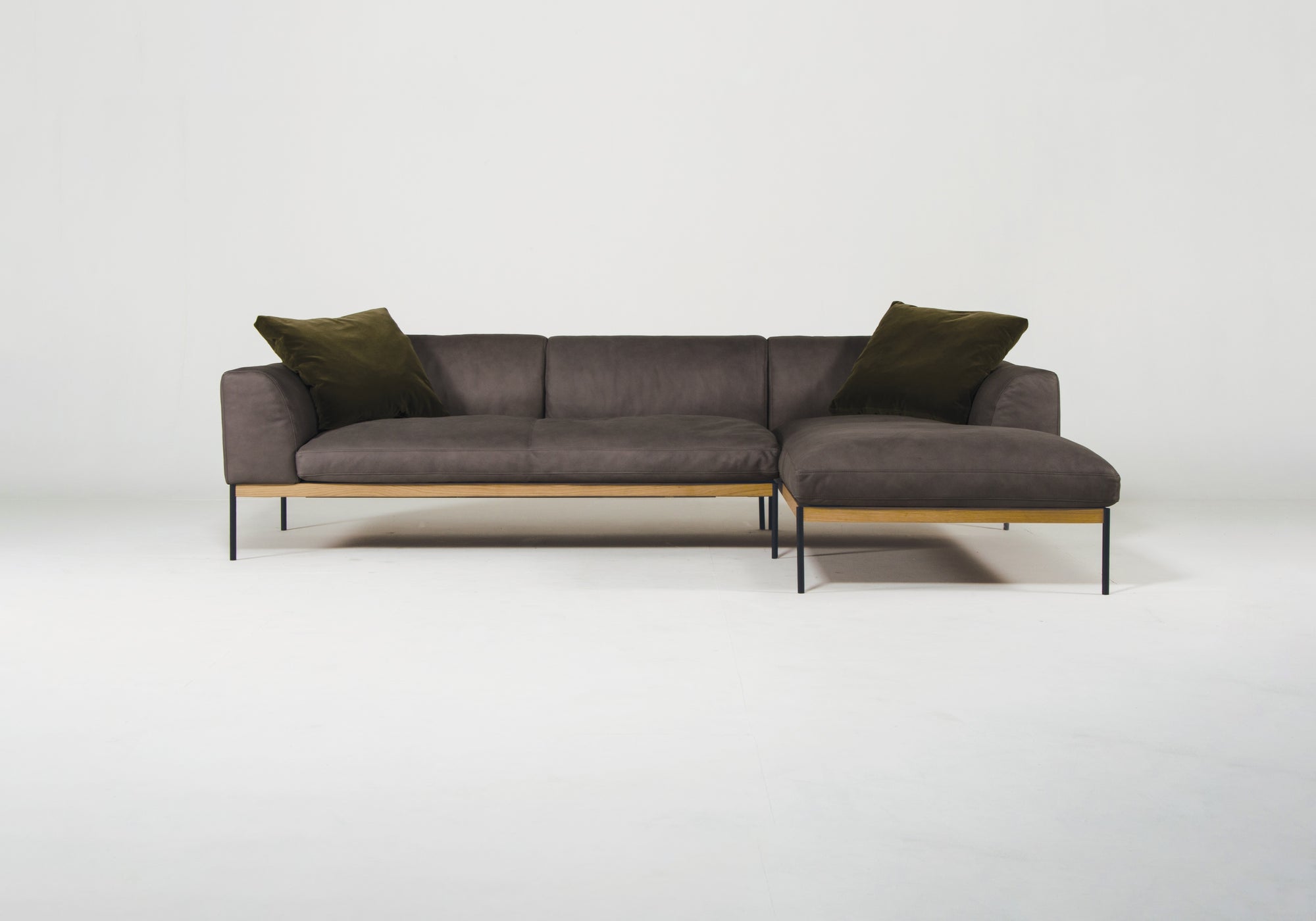 The Wooden Stories Department Modular Sofa | Leather • M2 Right features a modern dark gray design, slim black metal legs, a solid American FSC-certified oak base, and comes with two dark green throw pillows, shown on a plain white background.