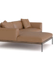 The Department Modular Sofa | Leather • M3 Left by Wooden Stories is a modern tan leather sectional with two seat cushions, matching back pillows, and slim black metal legs on a solid wood base, shown against a white background.