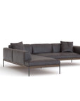 The Wooden Stories Department Modular Sofa | Leather • M4 Left features a modern dark gray design, solid wood base, slim metal legs, a left chaise lounge, and two matching throw pillows, shown against a plain white background.