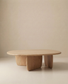 The Eden Coffee Table by Wooden Stories features a modern, oval solid wood design with three thick curved legs, highlighting Scandinavian simplicity against a neutral beige background.