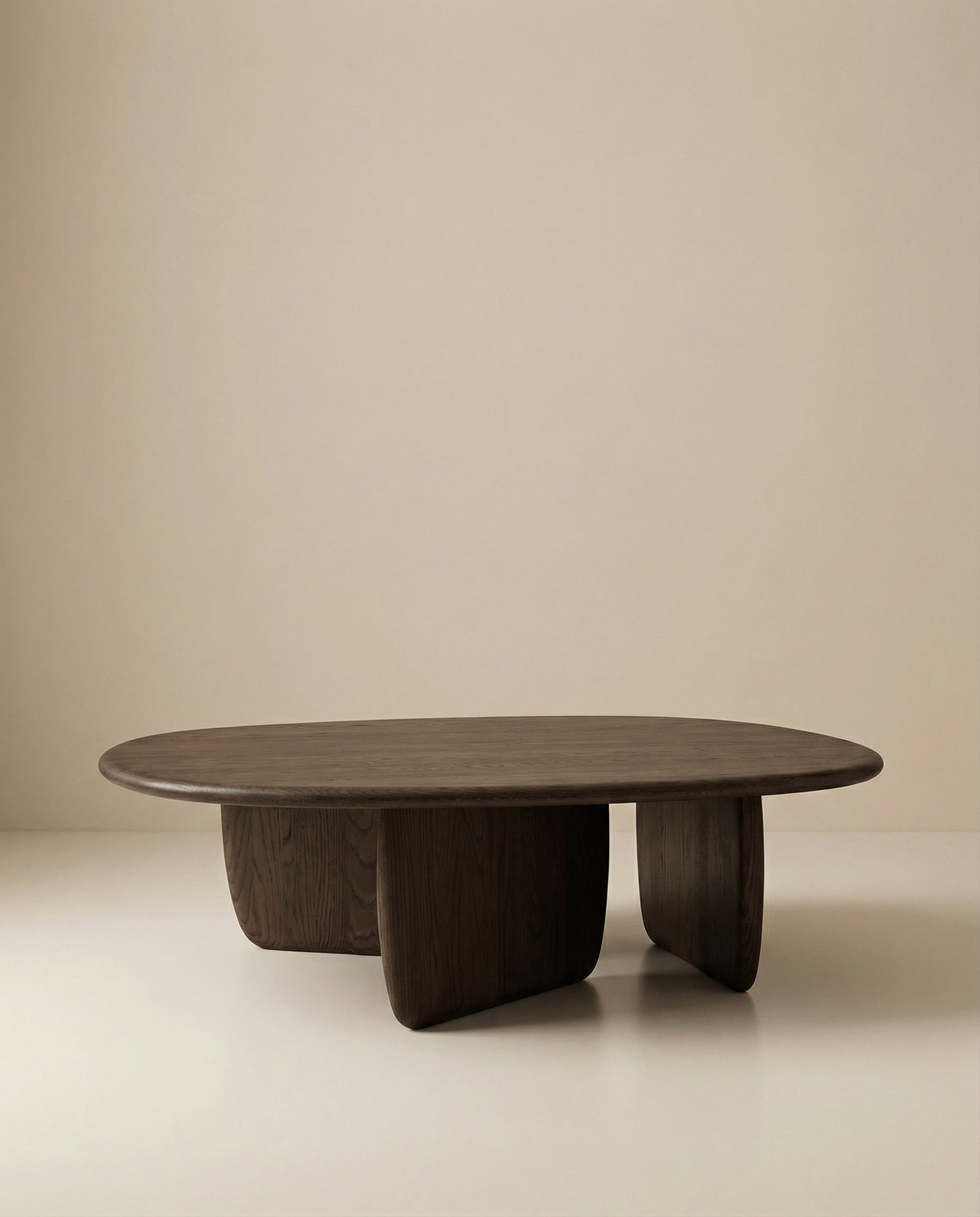 The Eden Coffee Table by Wooden Stories is a low, oval-shaped solid wood table with three wide, rounded legs and a smooth, minimalist design inspired by Scandinavian simplicity, shown against a plain beige background.