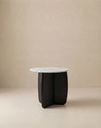 The Eden Side Table | Stone Top by Wooden Stories features a modern round white marble top and a sculptural solid American oak base, set against a neutral beige background to embody Scandinavian simplicity.