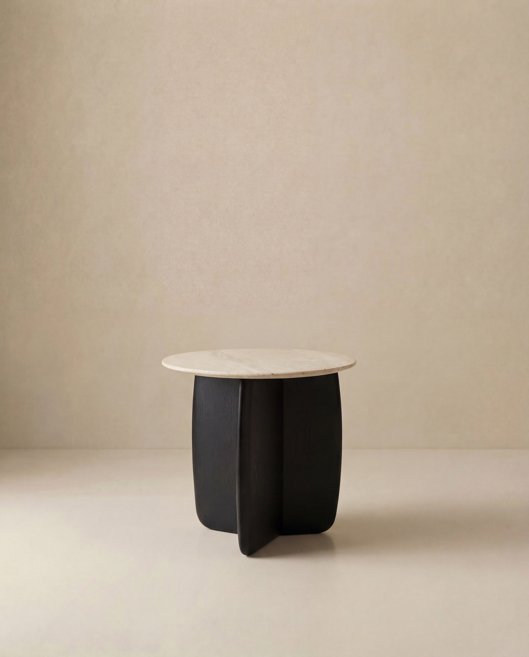 The Eden Side Table | Stone Top by Wooden Stories features a modern round beige stone top and a dark, curved solid American oak base, shown against a plain light beige background.