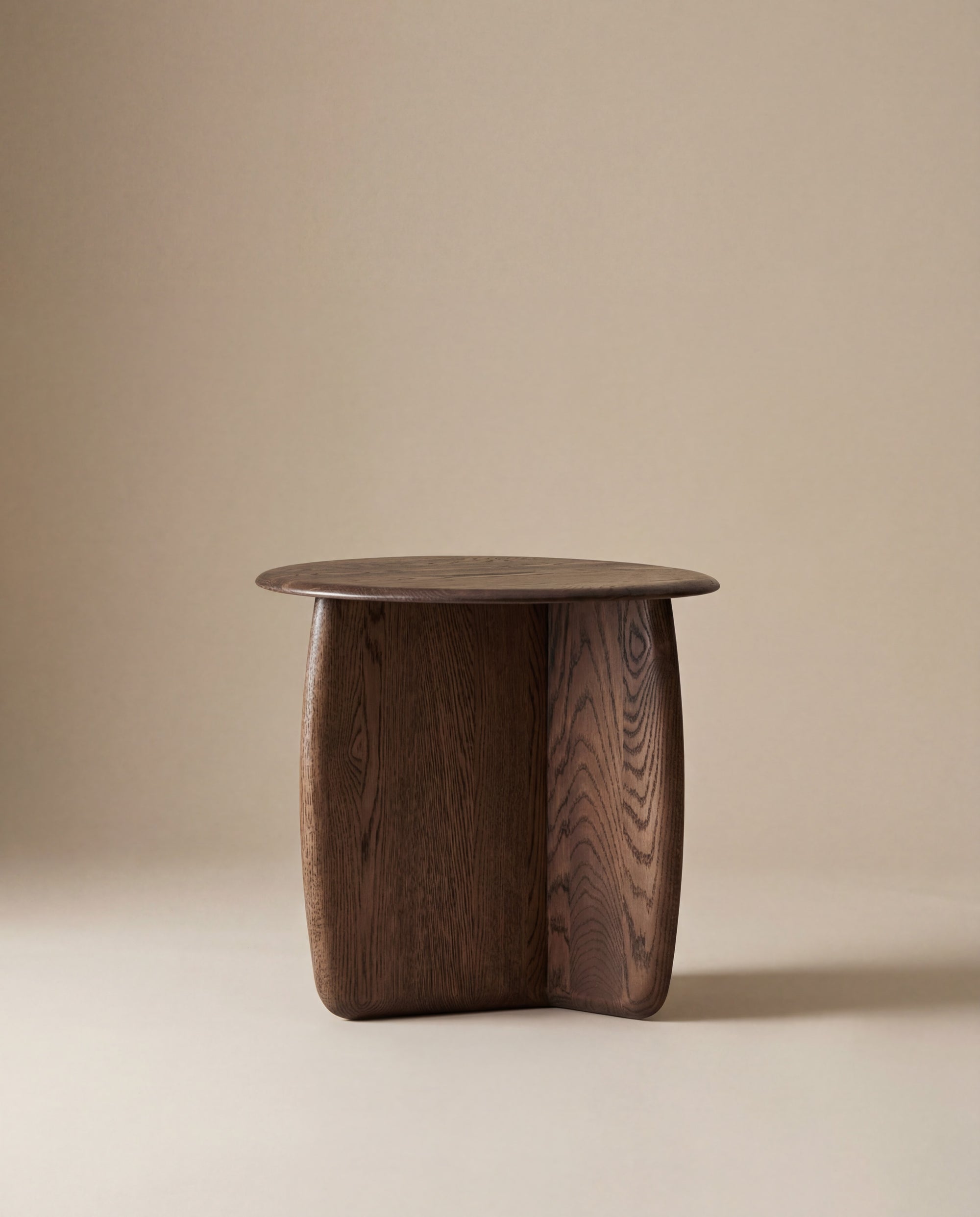 The Eden Side Table by Wooden Stories features a modern design with a smooth, round American oak top and sculpted curved legs, shown against a plain beige background.