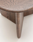 Close-up of the Wooden Stories Eden Side Table, a Scandinavian-inspired piece with smooth, rounded edges, intersecting legs, and natural wood grain set against a light-colored background.