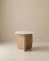 The Eden Side Table | Stone Top by Wooden Stories features a white marble top and light American oak base with intersecting curved panels, embodying Scandinavian simplicity against a beige backdrop.