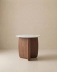 The Eden Side Table | Stone Top by Wooden Stories features a round white marble top and a curved American oak base, displayed against a plain beige background.
