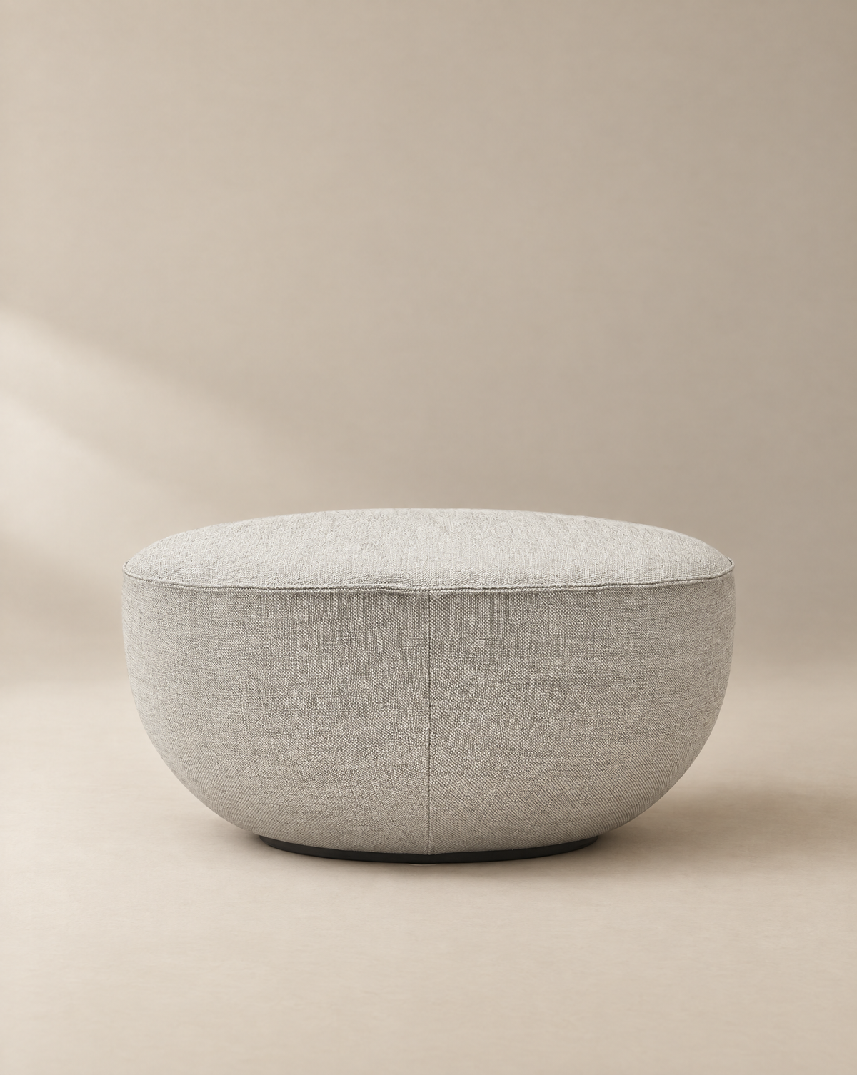 A light gray, oval-shaped Fable Ottoman | Fabric by Wooden Stories from the Danish Collection is displayed on a neutral background with soft lighting, highlighting its smooth, minimalist design.