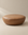 The Fable Ottoman | Leather by Wooden Stories features a round silhouette crafted from brown leather with smooth stitching, showcased on a neutral background to highlight its simple and modern design.