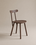 The Figura Dining Chair by Wooden Stories features an espresso oak finish, a round seat, four straight legs, and a curved backrest, shown against a plain beige background.