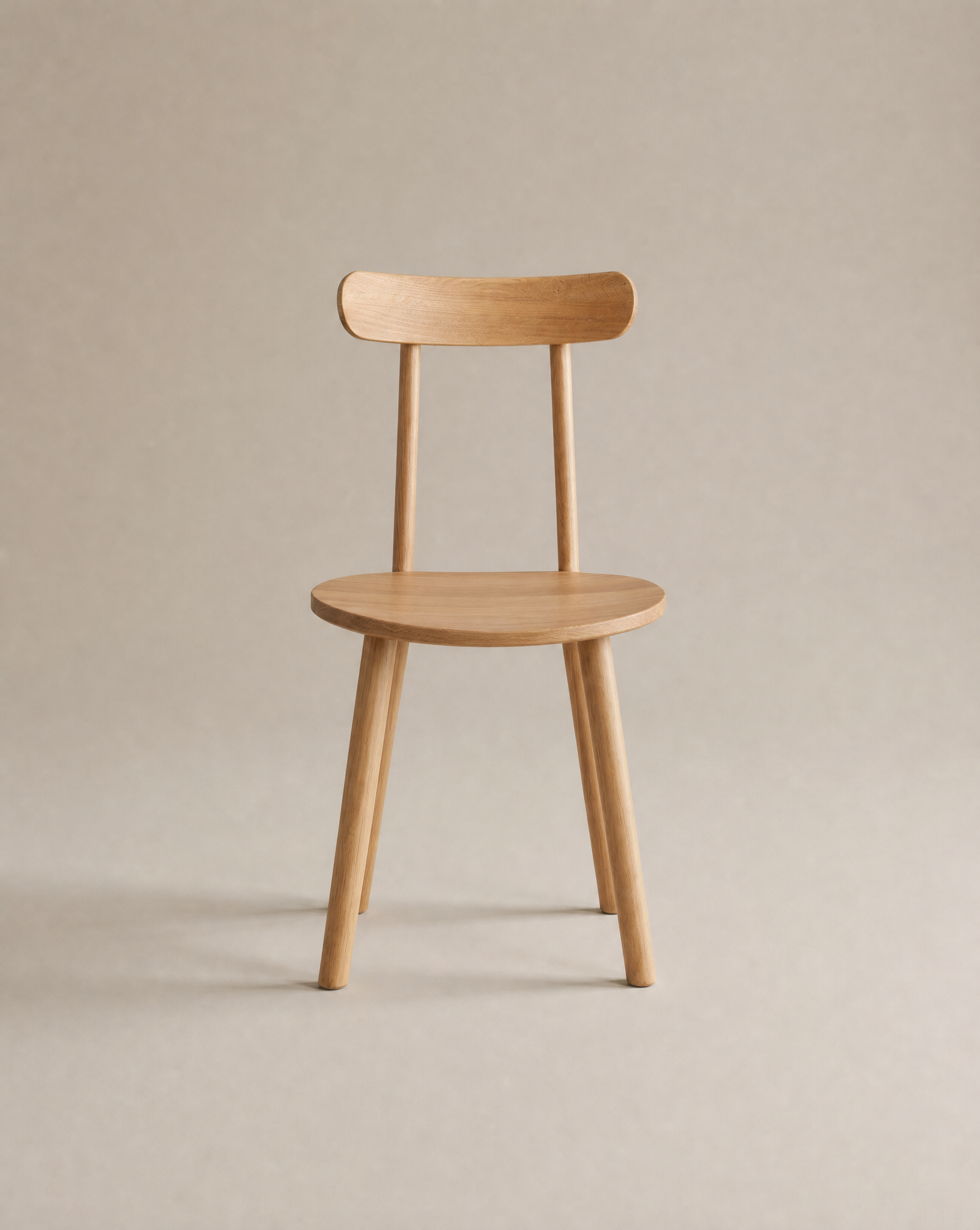 The Figura Dining Chair | Light Oak by Wooden Stories features a simple wooden design with four legs, a round seat, and curved backrest—an elegant example of Scandinavian style set against a plain neutral background.