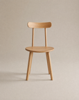 The Figura Dining Chair | Light Oak by Wooden Stories features a simple wooden design with four legs, a round seat, and curved backrest—an elegant example of Scandinavian style set against a plain neutral background.
