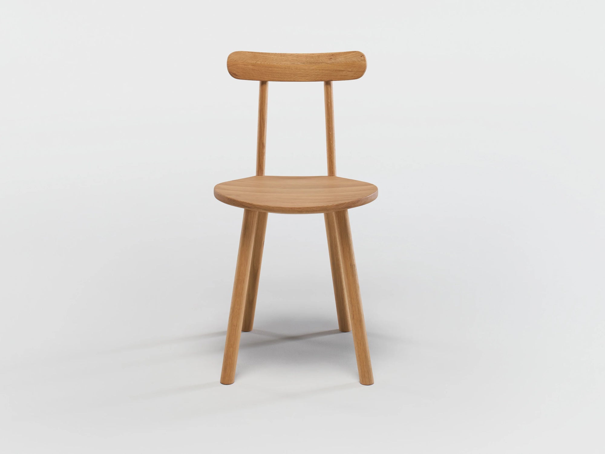 The Figura Dining Chair by Wooden Stories features a light oak finish, curved backrest, three legs, and flat seat. Heritage woodworking-inspired design shown against a white background.