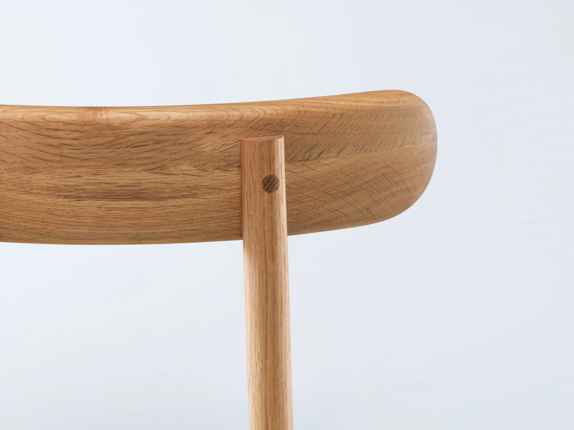 Close-up of the backrest and support of the Wooden Stories Figura Dining Chair in Light Oak, showcasing smooth solid wood craftsmanship against a plain white background—a timeless piece inspired by heritage woodworking.