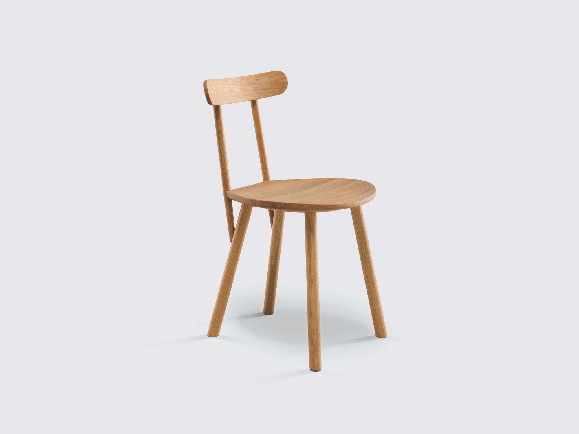The Figura Dining Chair by Wooden Stories features a solid light oak build, four legs, a round seat, and a narrow curved backrest, highlighting heritage woodworking against a plain light gray background.