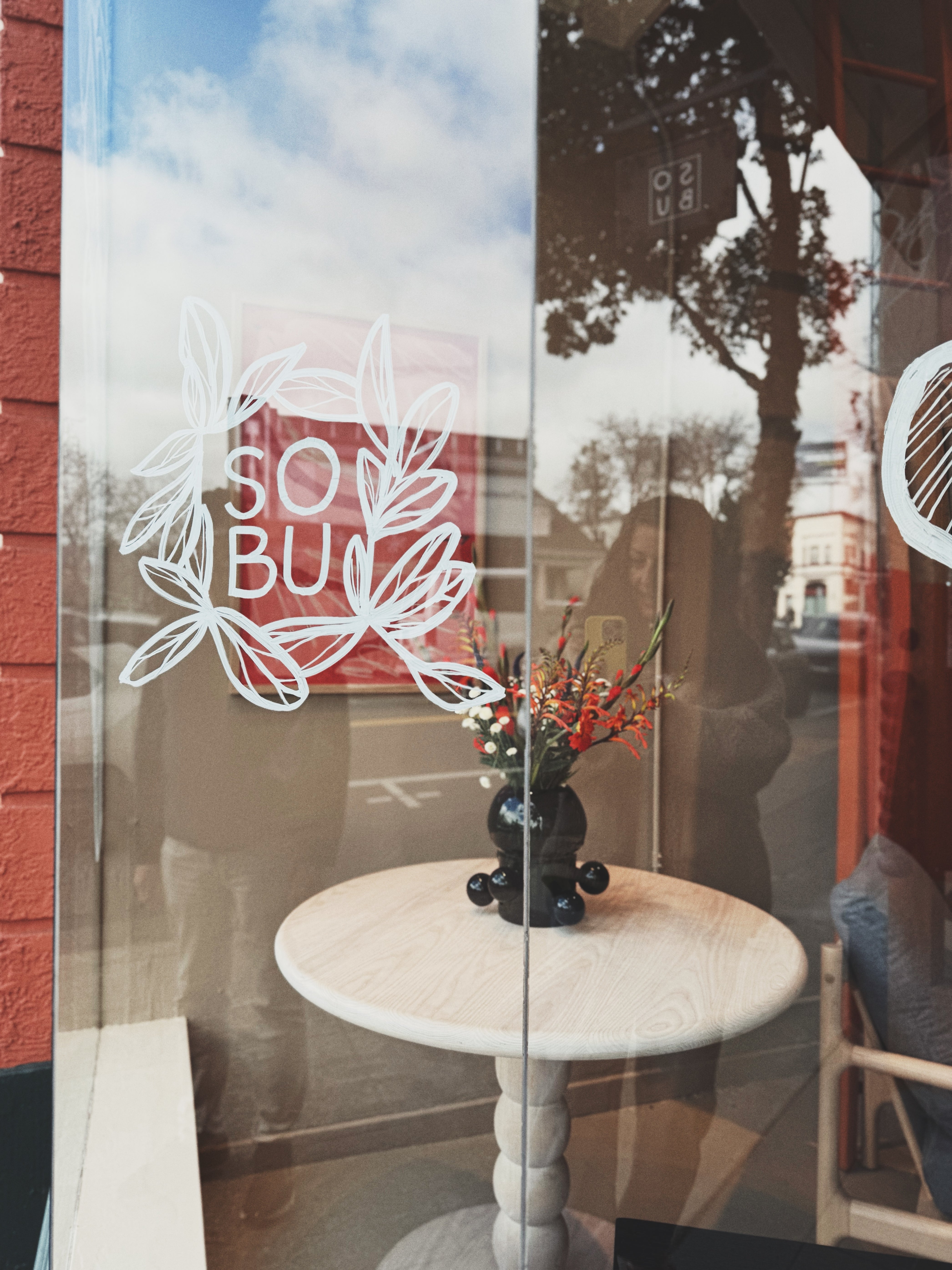 Sobu Storefront, featuring a large display window with white floral illustrations and SOBU in the center.