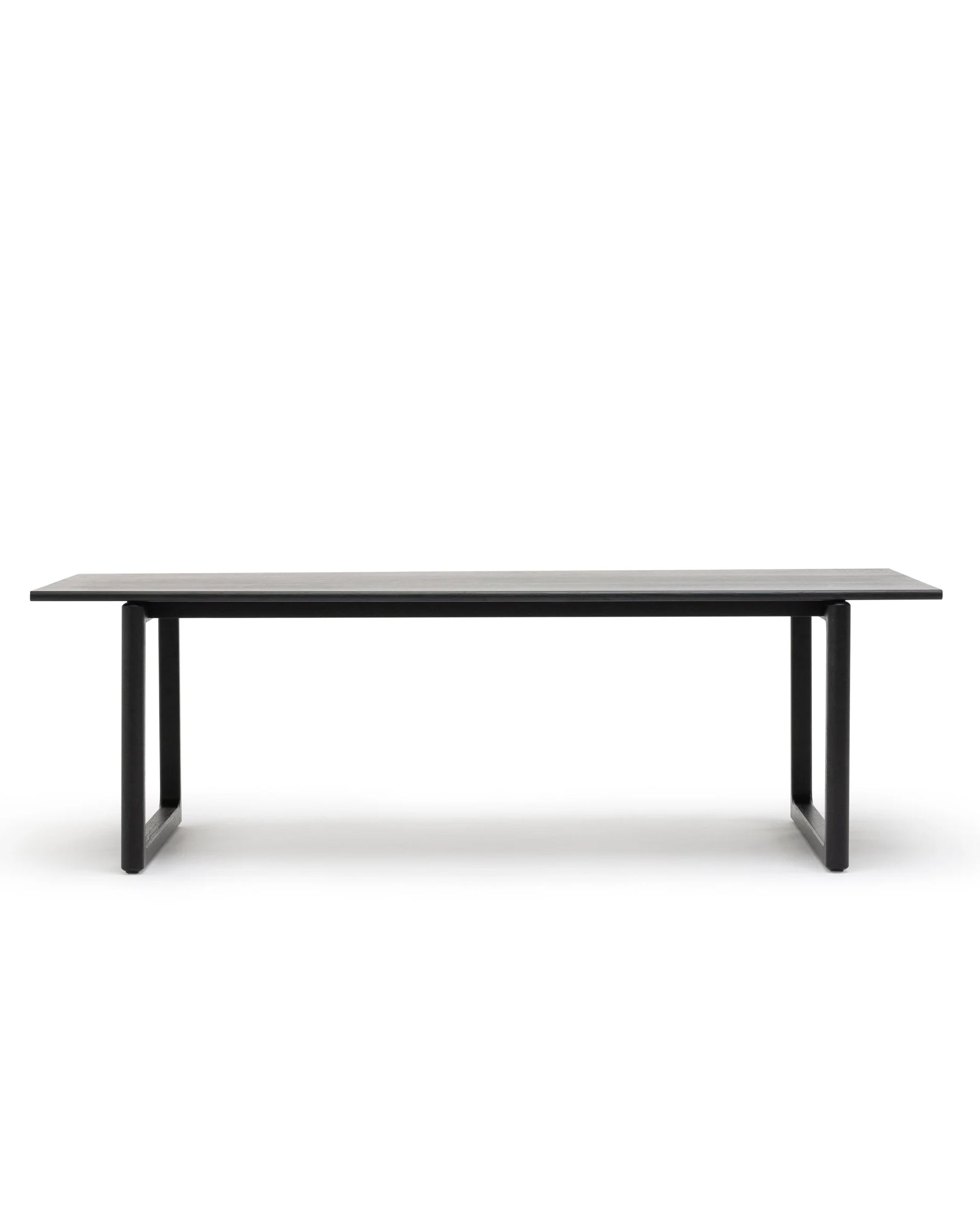 The Hover Dining Table | Black Oak by Wooden Stories features a minimalist Scandinavian design with straight, thick legs at each end, shown against a plain white background.