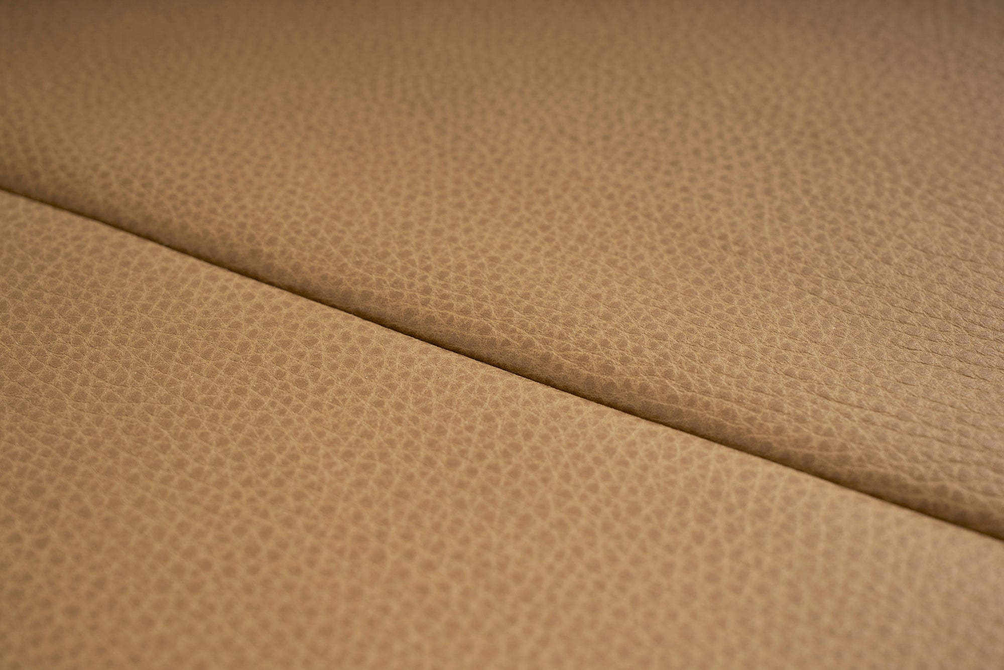 Close-up of light brown leather upholstery with a subtle texture and diagonal seam, showcasing the refined details of the contract-grade Hover Bench | Leather Seat by Wooden Stories.