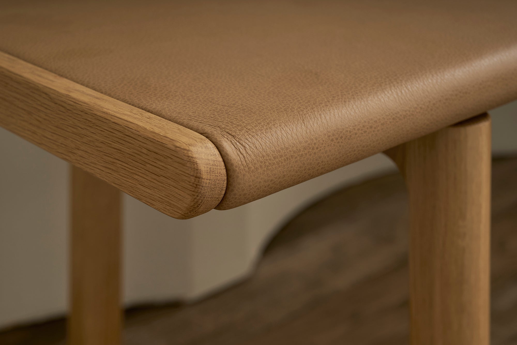 Close-up of the Hover Bench | Leather Seat by Wooden Stories shows a smooth tan leather seat, rounded edges, and natural wood grain, highlighting the elegant craftsmanship and contract grade quality.