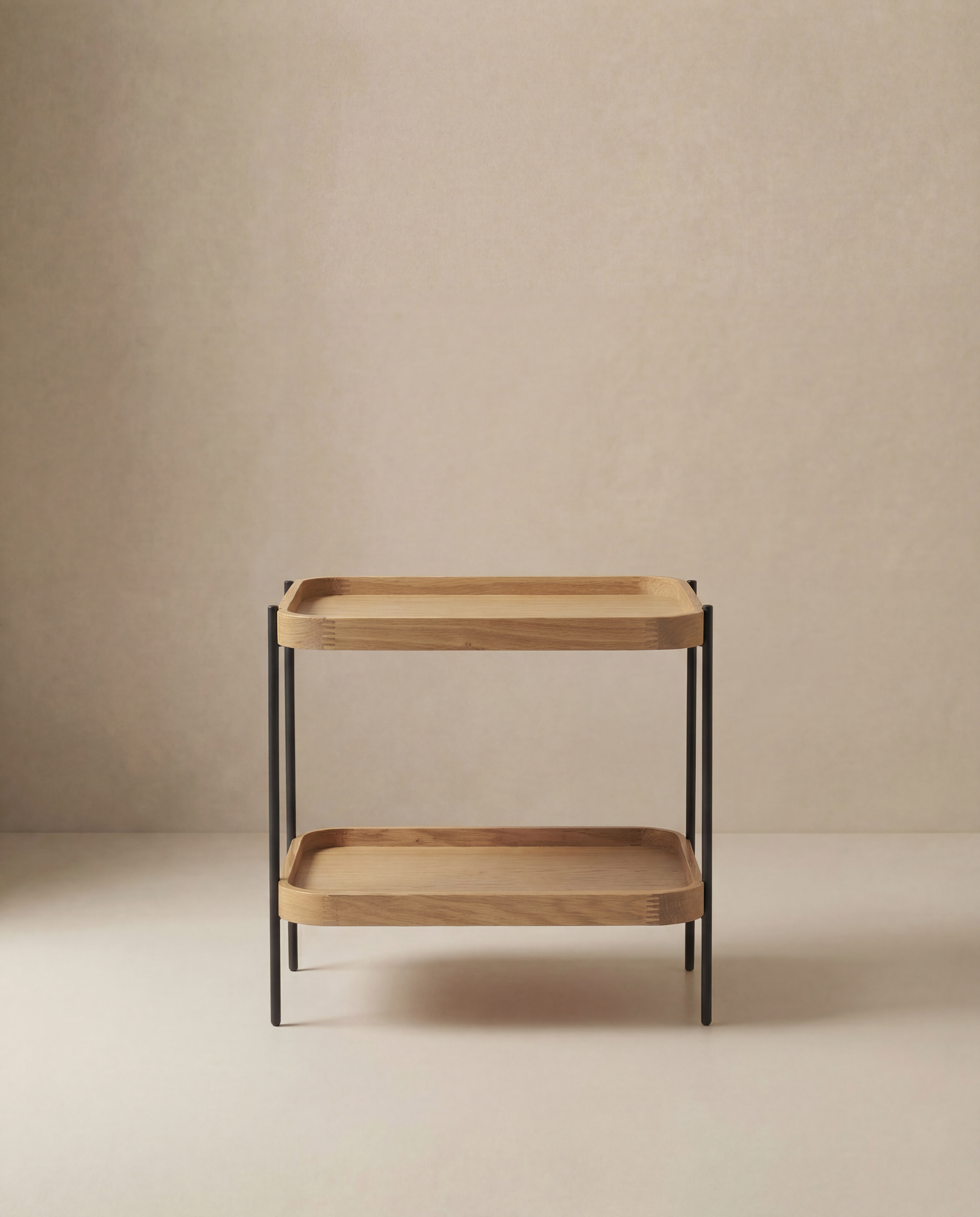 The Humla Rectangular End Table by Wooden Stories is a minimalist wooden side table with two rectangular shelves and slim black metal legs, inspired by Danish design and set against a neutral beige background.