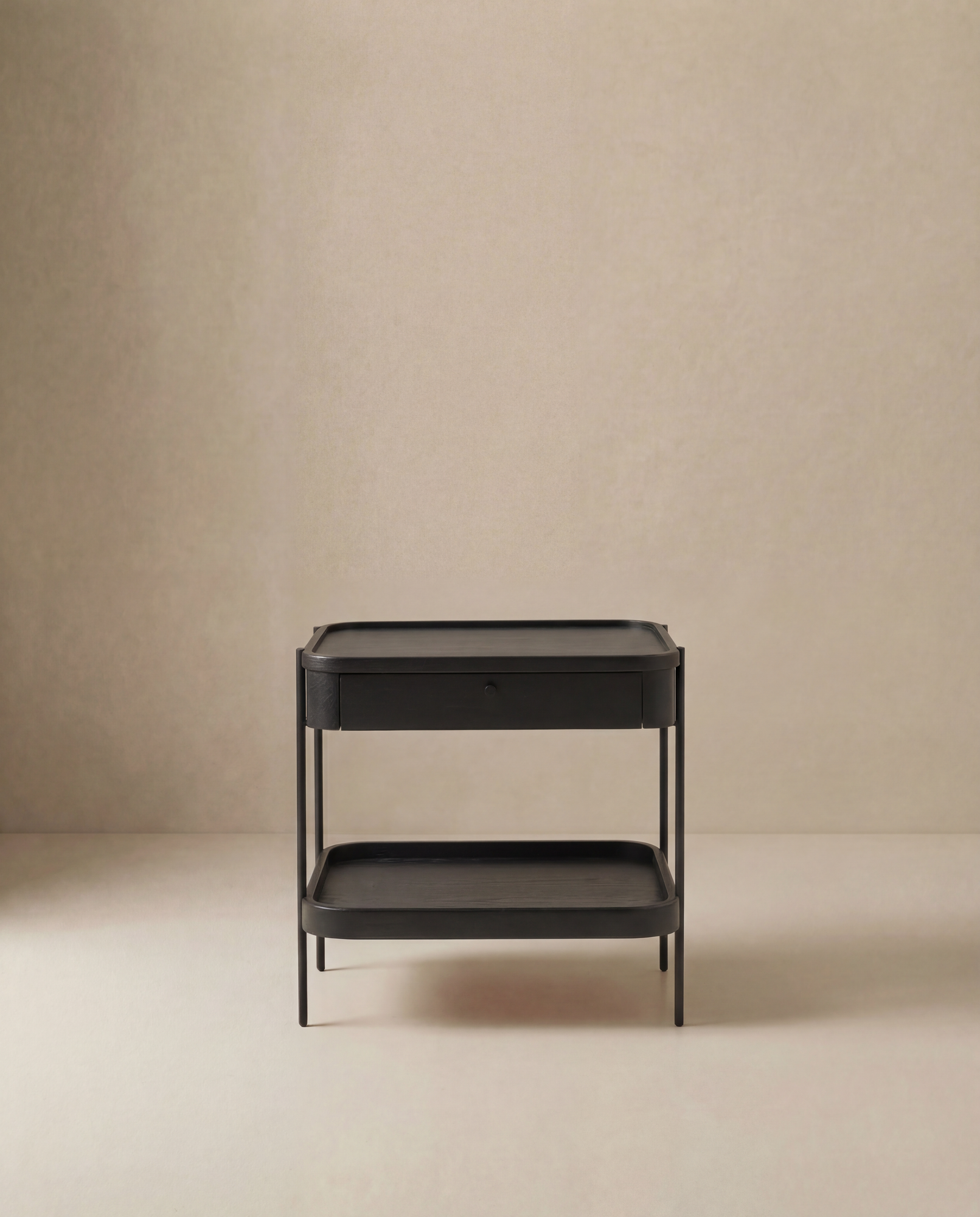 The Wooden Stories Humla Side Table With Storage features a minimalist black metal frame, solid wood drawer, and open lower shelf, shown against a plain beige background.