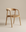 The Inlay Dining Chair | Leather by Wooden Stories is a modern wooden chair from the Danish Collection, crafted from solid oak with a curved backrest, armrests, and a padded leather seat, showcased against a beige background.