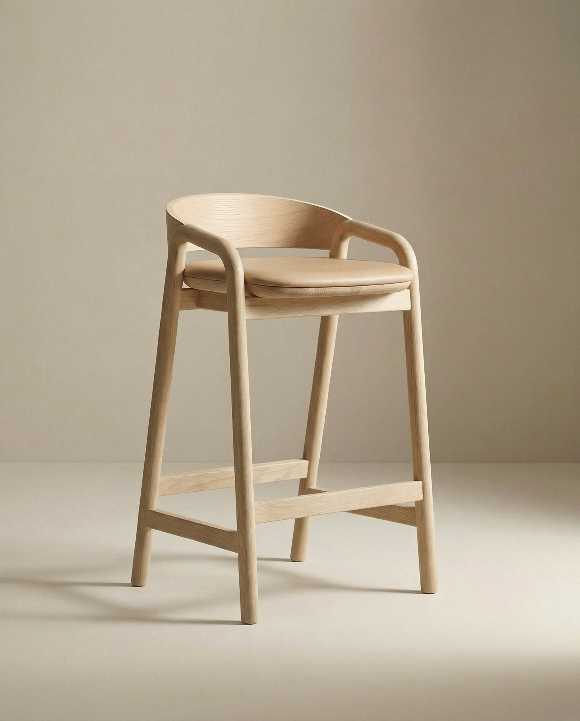 The Inlay Counter Stool | Leather Seat by Wooden Stories features a light wood finish, curved backrest, armrests, and minimalist design—part of the Danish Collection—shown here set against a neutral beige background.