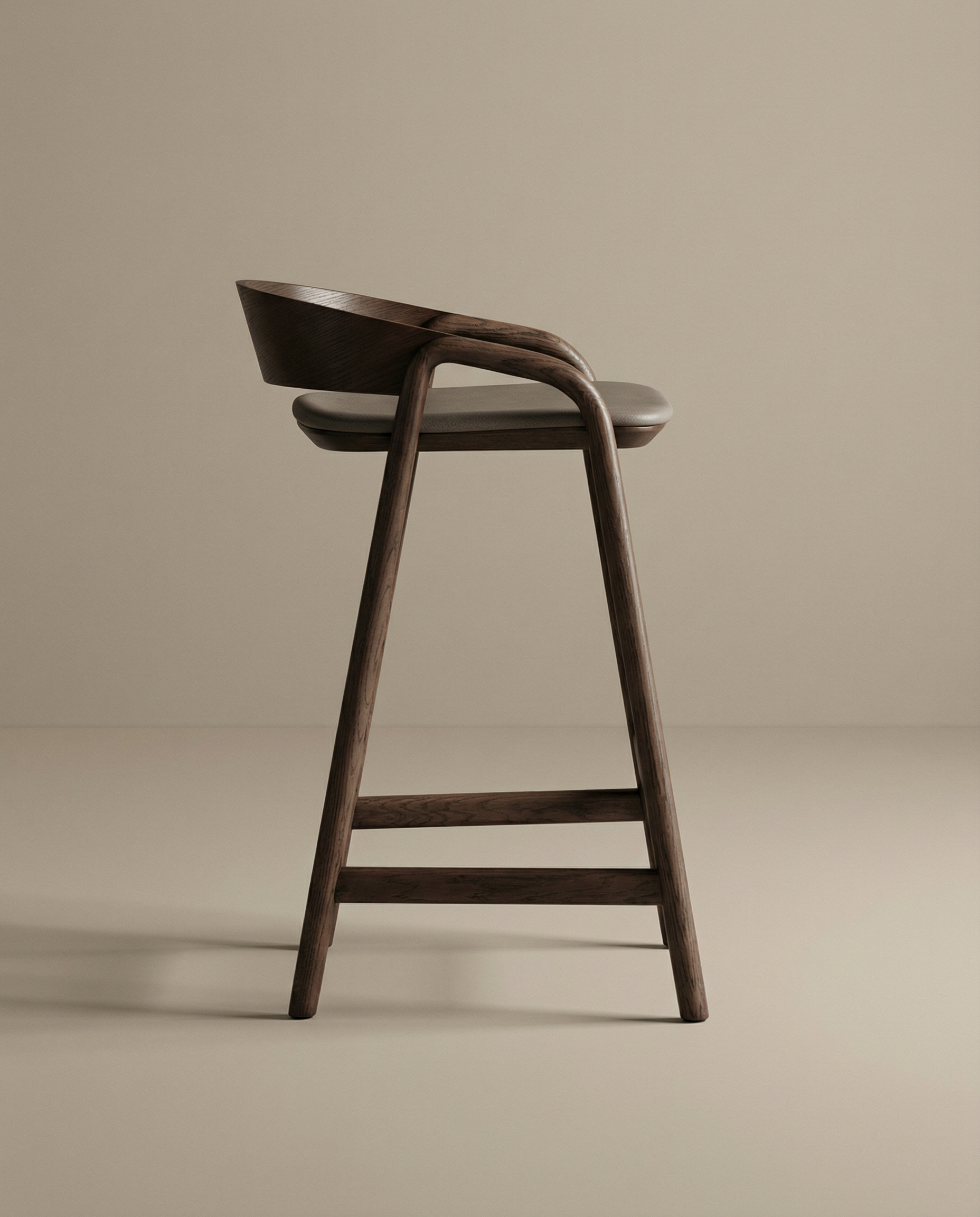 The Inlay Counter Stool | Leather Seat by Wooden Stories is a modern solid oak bar stool with a curved backrest and round leather seat, featuring smooth lines and minimalist design. Shown in profile against a beige background.