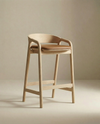 The Inlay Counter Stool | Leather Seat by Wooden Stories features a modern design with a curved backrest, padded leather seat, and clean lines, shown here against a plain beige background.
