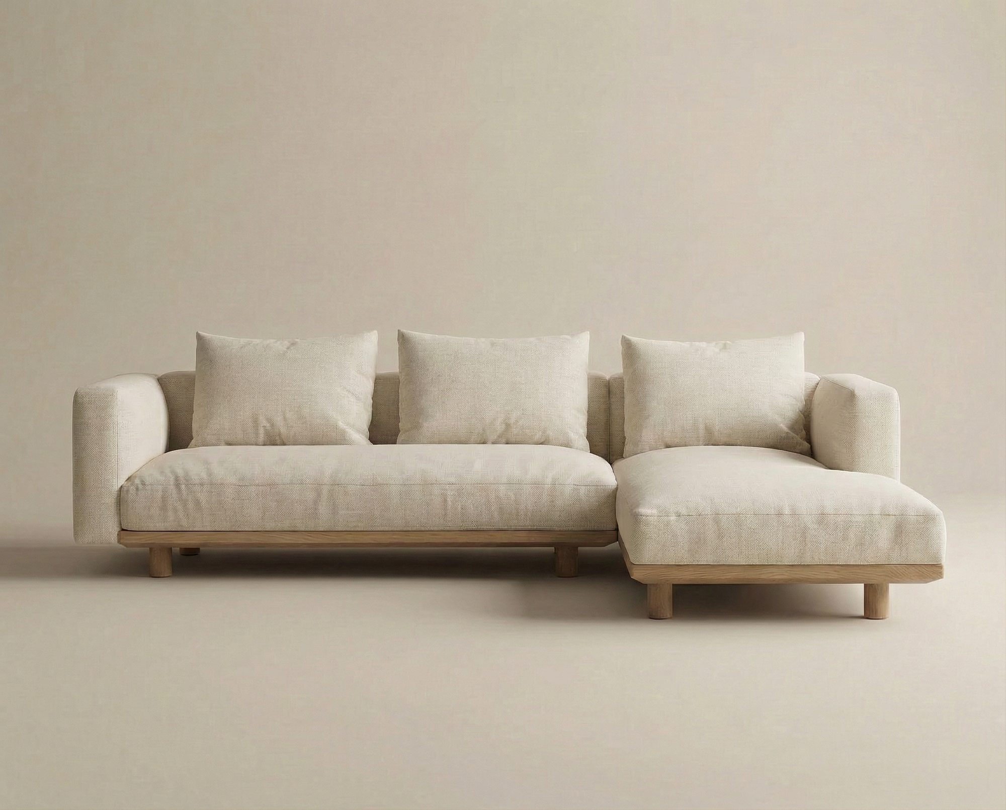 The Islet Modular Sofa | Fabric • M1 by Wooden Stories is a modern beige sectional with wooden legs, three back cushions, and a right-side chaise lounge, shown against a plain light background.
