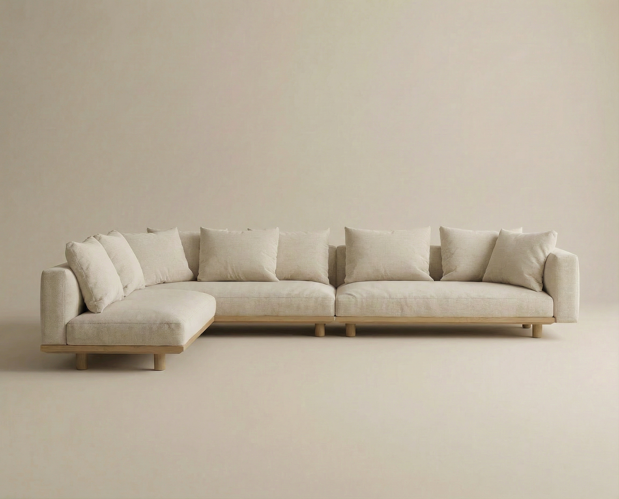 The Islet Modular Sofa | Fabric • M2 by Wooden Stories features light beige upholstery, multiple matching cushions, wooden legs, and a minimalist design, set against a neutral background.