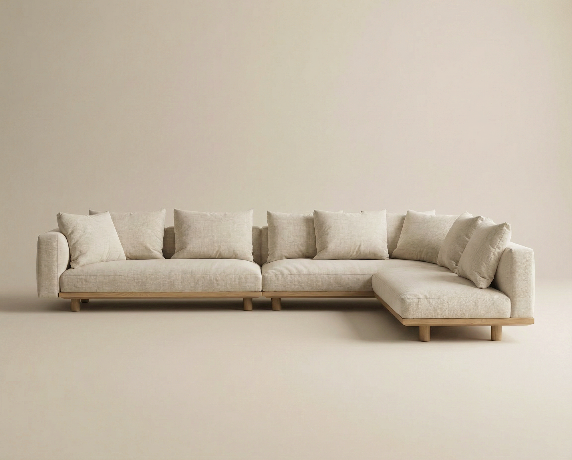 The Islet Modular Sofa | Fabric • M2 by Wooden Stories is a modern L-shaped beige sectional with wooden legs and multiple back cushions, shown against a plain beige background.